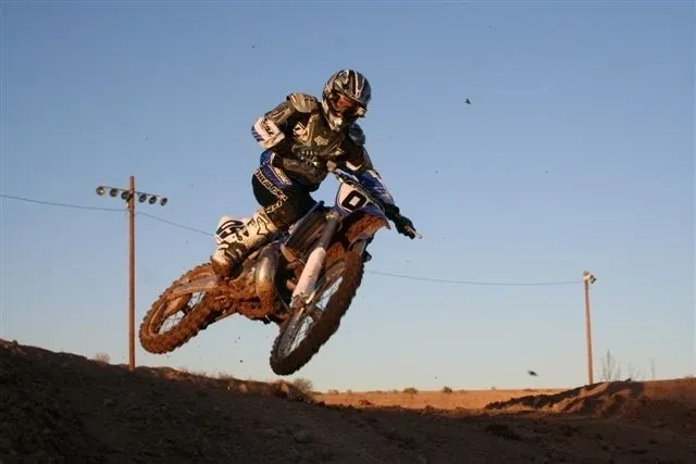 A person on a dirt bike jumping over a hill.