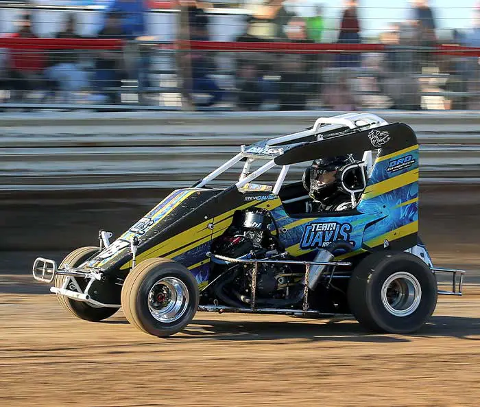 A racing car driving down the track in front of spectators.