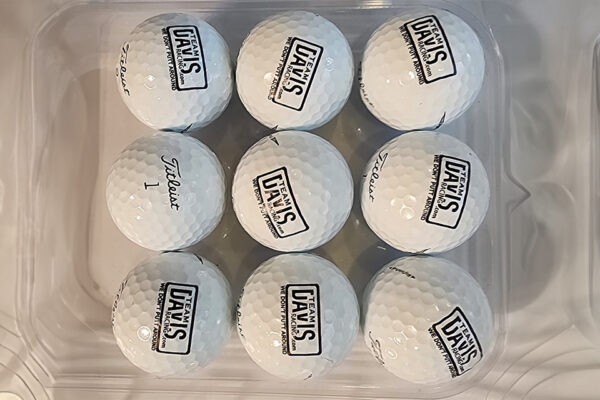 A close up of nine golf balls with logos