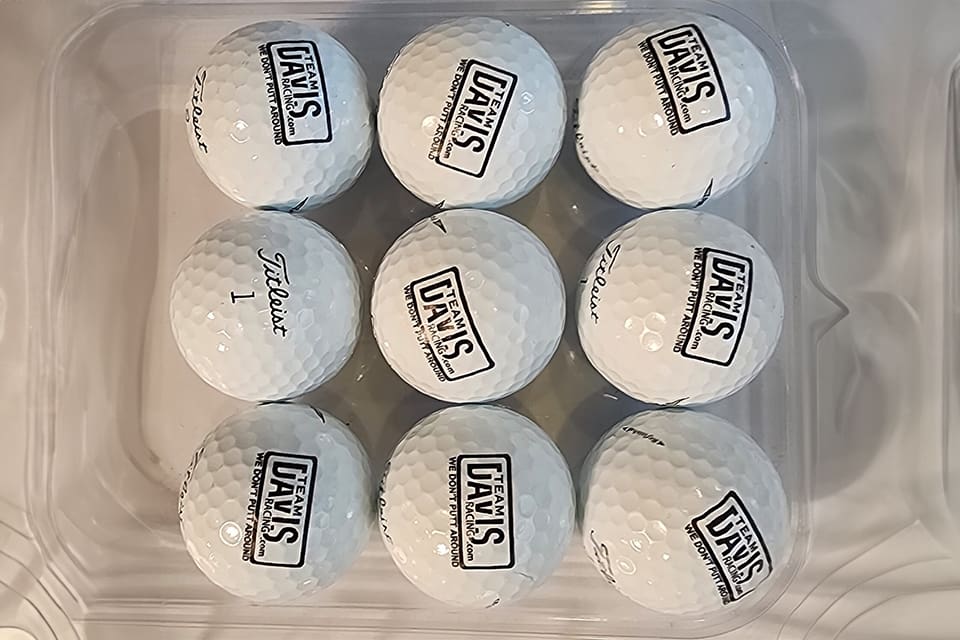 A close up of nine golf balls with logos