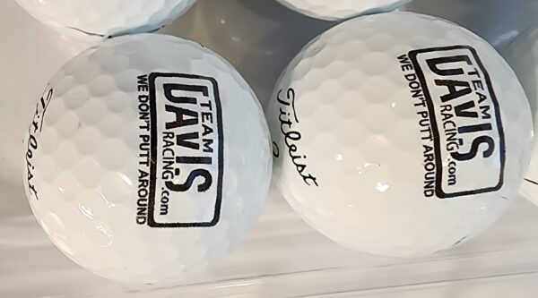 A close up of two golf balls with the team davis logo on them.