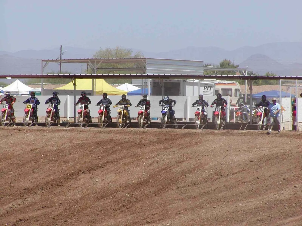 A group of people riding motorcycles on top of dirt.