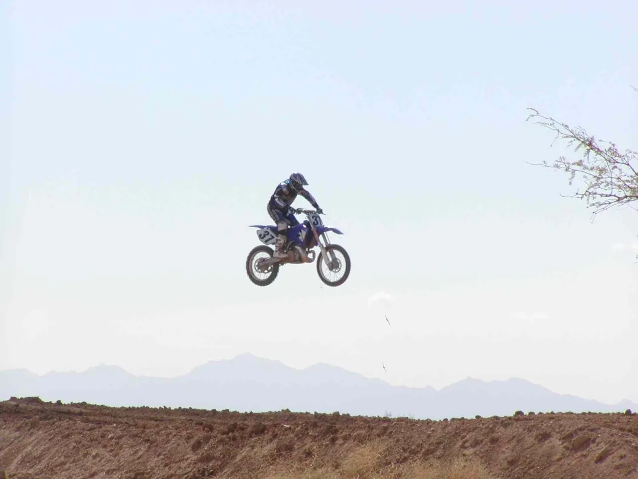 A person on a motorcycle jumping over some dirt.