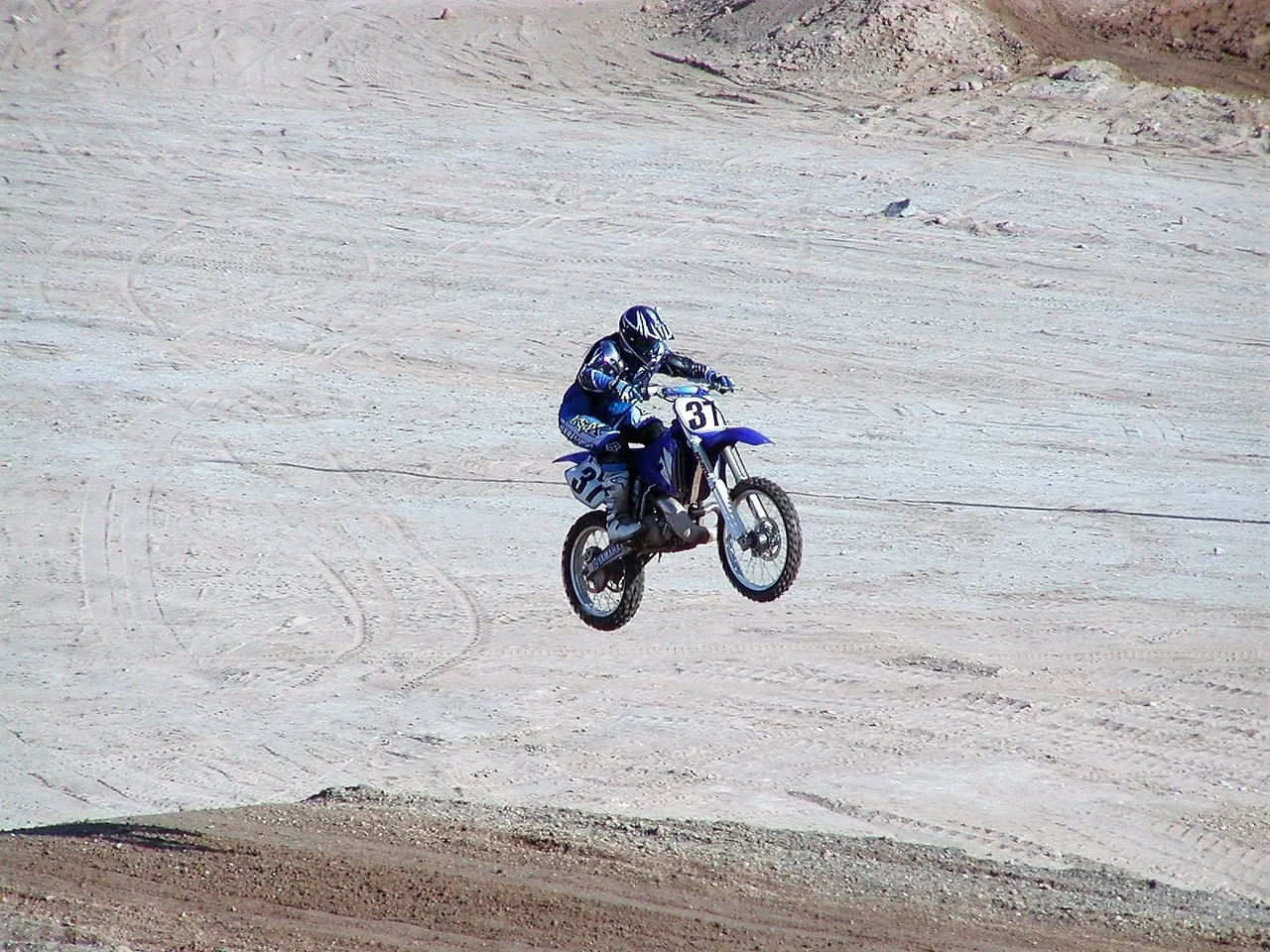 A person on a dirt bike jumping over some sand.