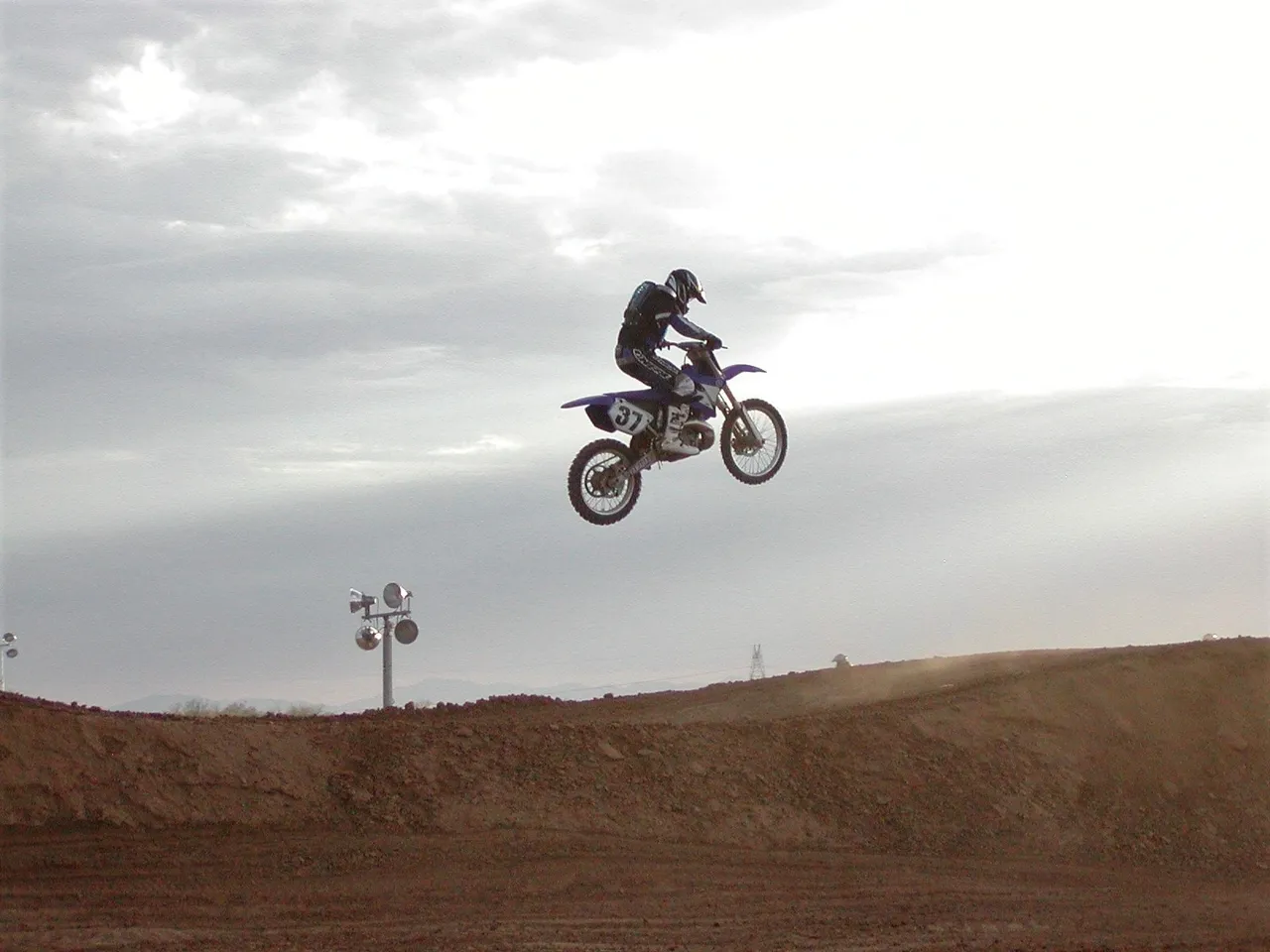 A person on a dirt bike jumping over a hill.