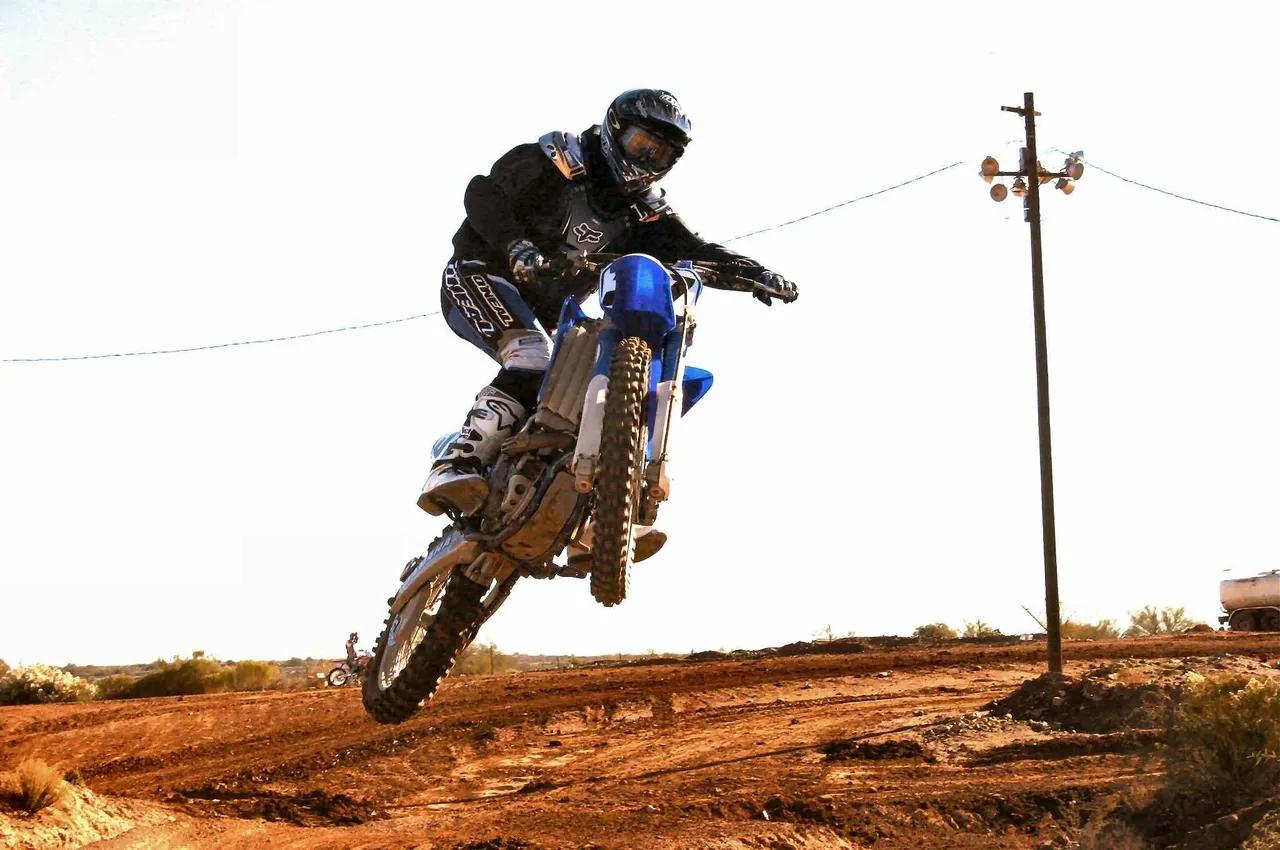 A person on a dirt bike jumping over a hill.