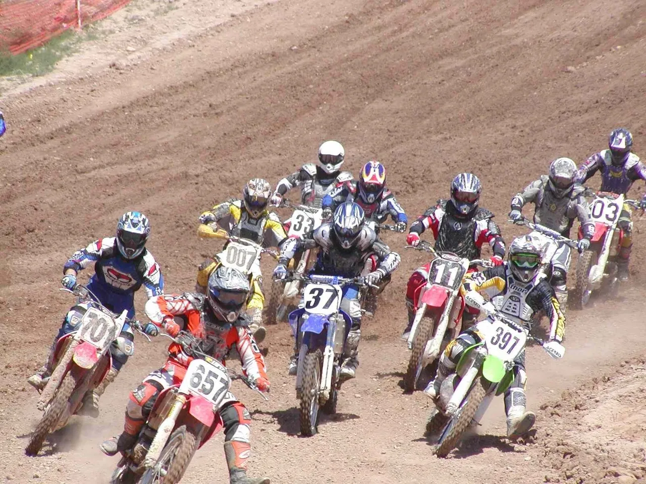 A group of dirt bike riders on the side of a track.